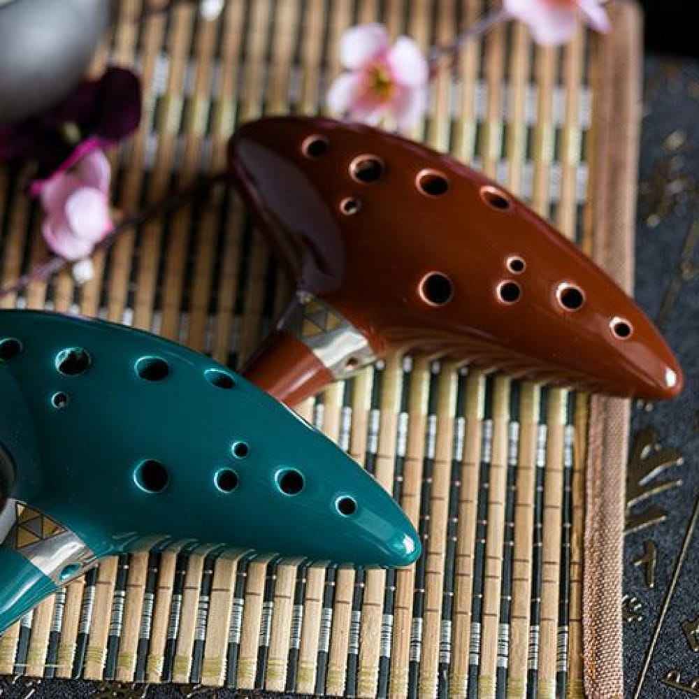 Two ceramic ocarinas in brown and teal with finger holes for music enthusiasts