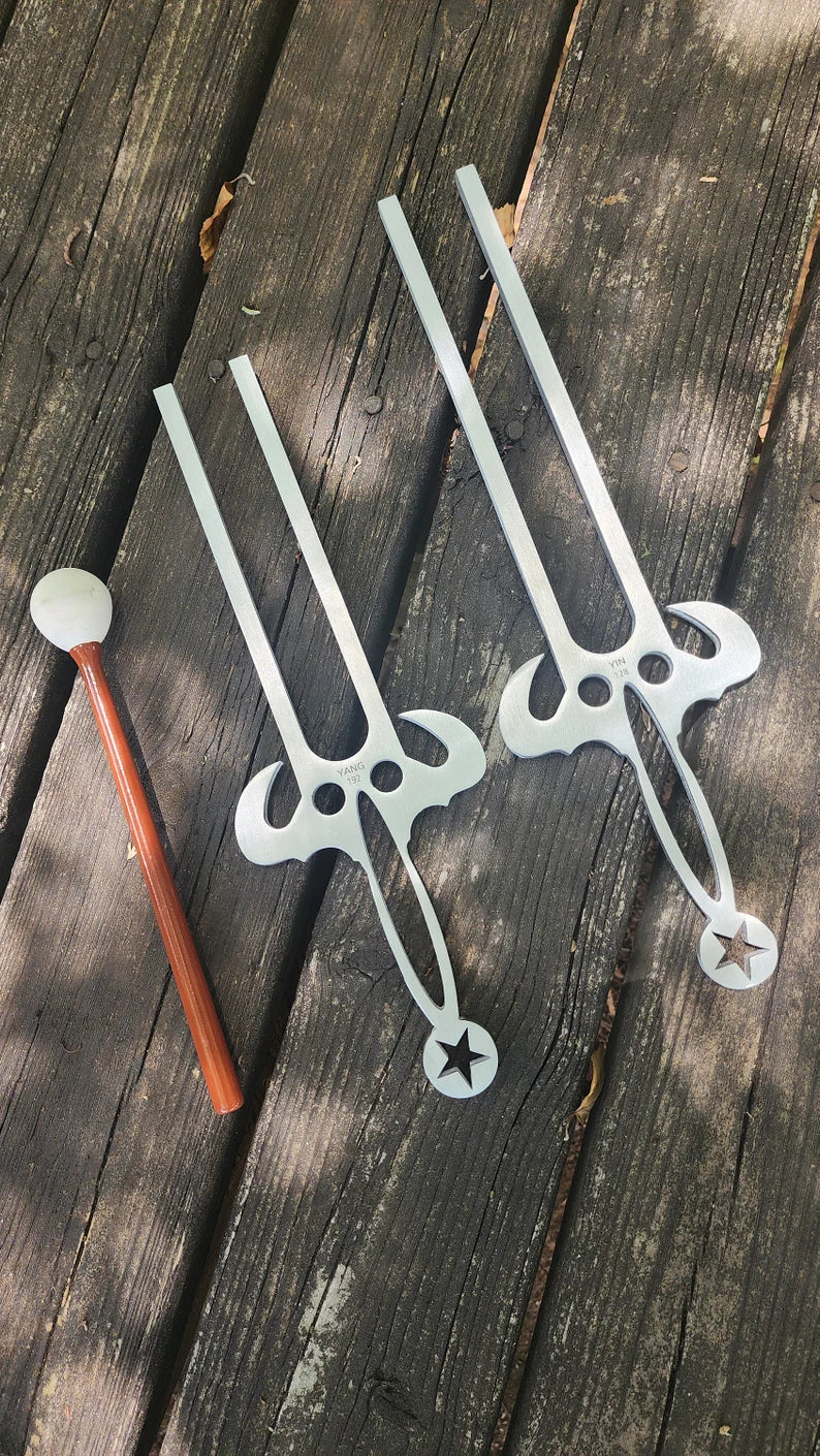Two 128 Hz and 192 Hz Large Tuning Forks with pencil on white background