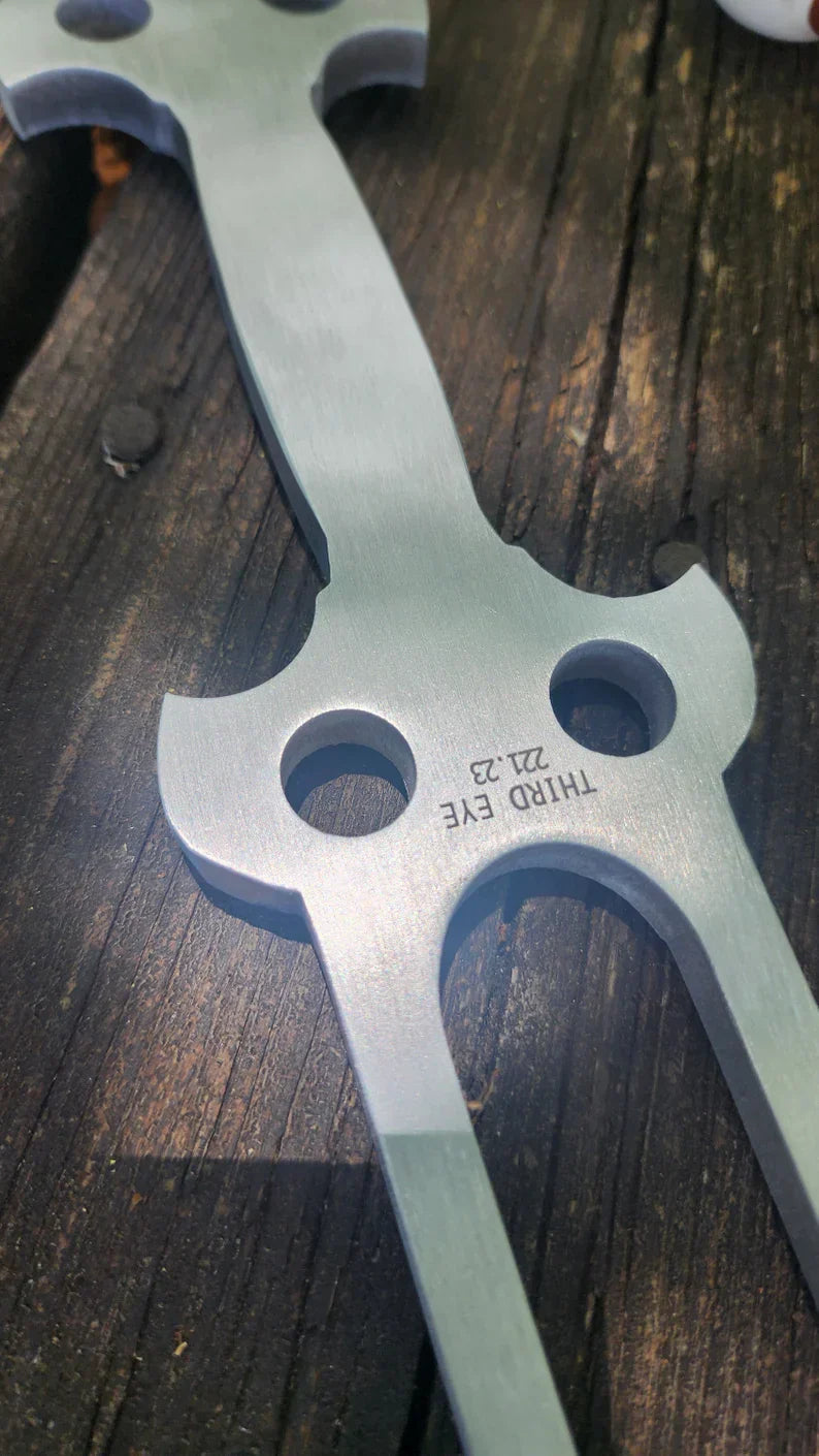 Metal throwing star with circular holes next to 22 inch Double Trident Tuning Fork