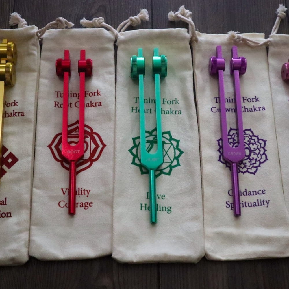 Colorful tuning forks with chakra symbols in cloth pouches for Mercury and Throat Chakra
