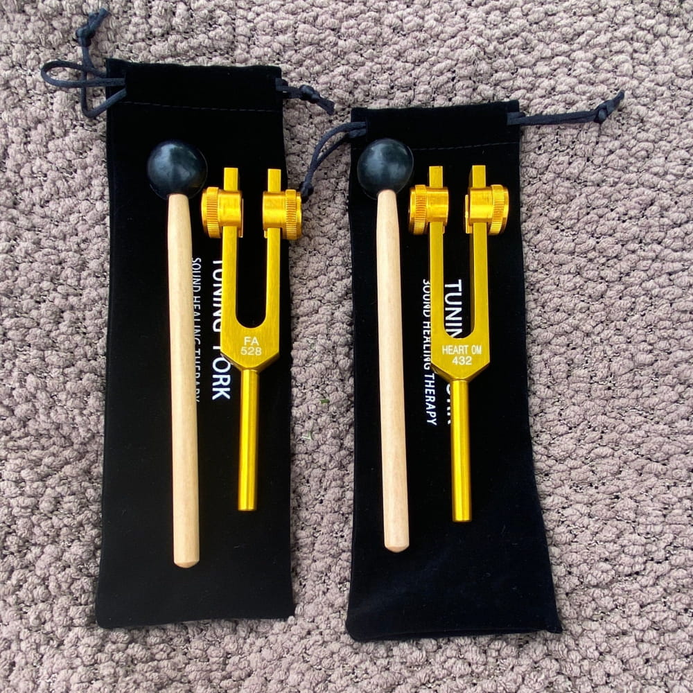 Two yellow tuning forks with wooden mallets in black pouches for healing therapy