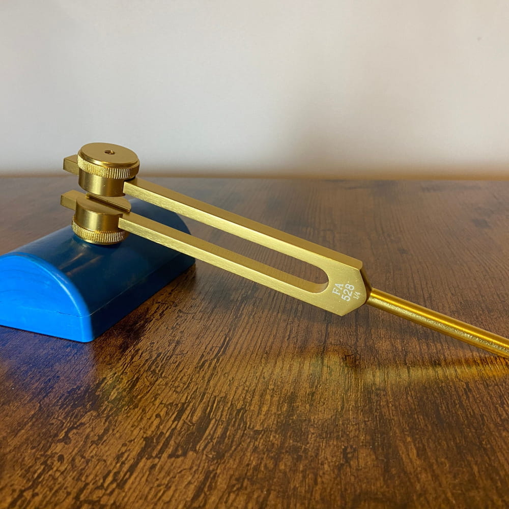 Golden tuning fork with blue base for 528 Hz healing therapy and chakra balancing