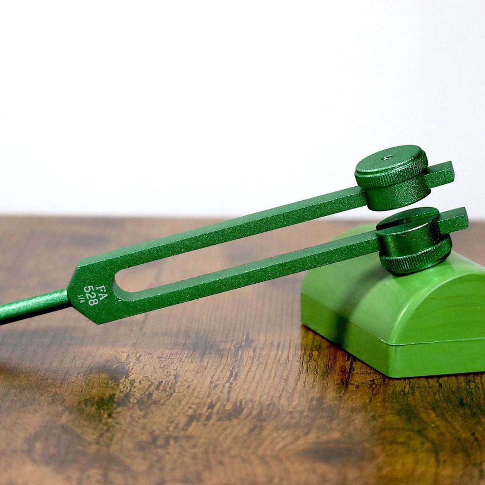 Green metal tuning fork with adjustable weights for healing therapy and chakra alignment