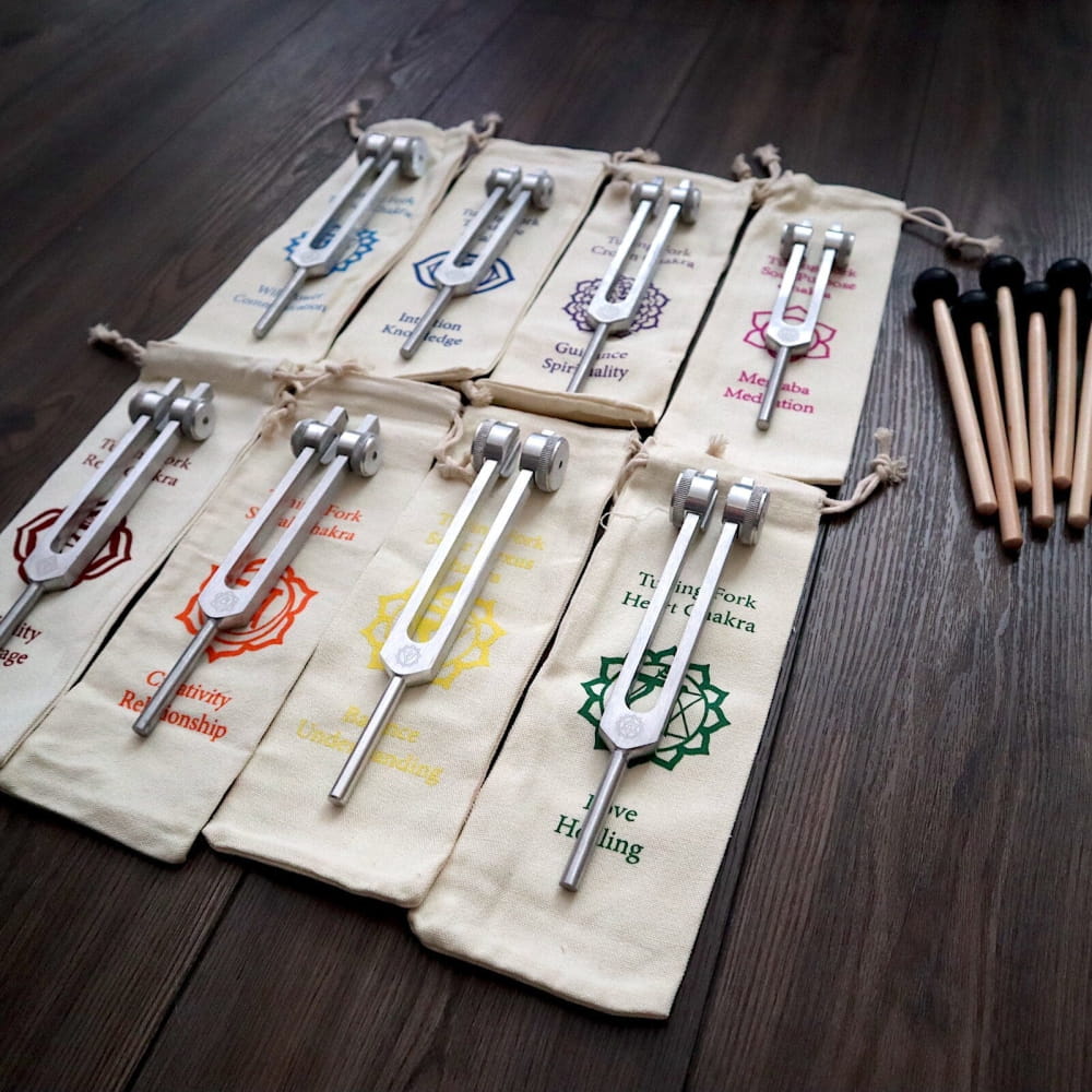 Collection of tuning forks in labeled pouches for chakra healing set on a surface