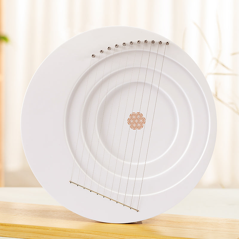 White plate with metallic strings and geometric design on Full Moon Lyre Harp Instrument