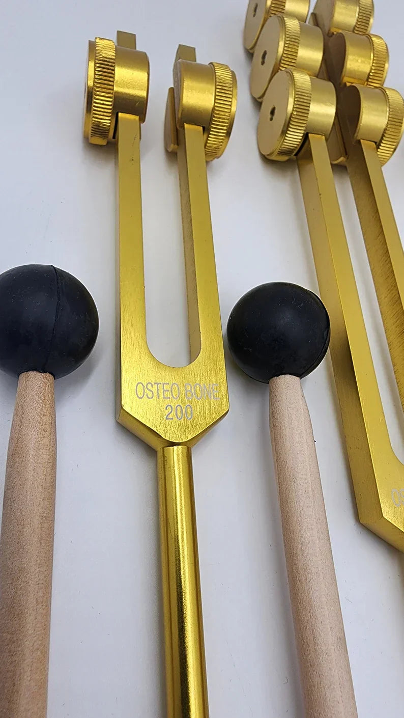 Gold-colored tuning forks with wooden mallets in a Weighted Osteo Tuning Fork Set