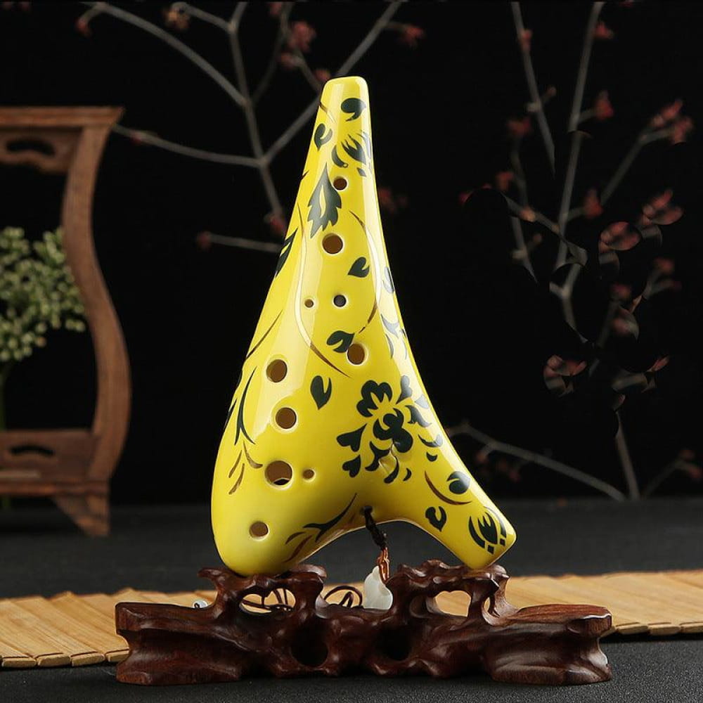 Yellow ceramic 12 Hole Alto C Ocarina with floral designs on wooden stand