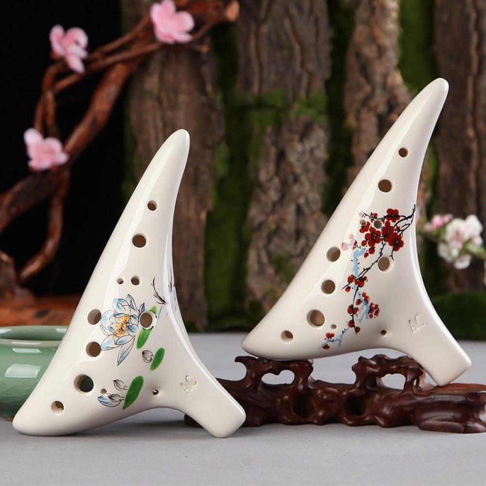 Two decorative white ceramic ocarina flutes with finger holes and floral designs