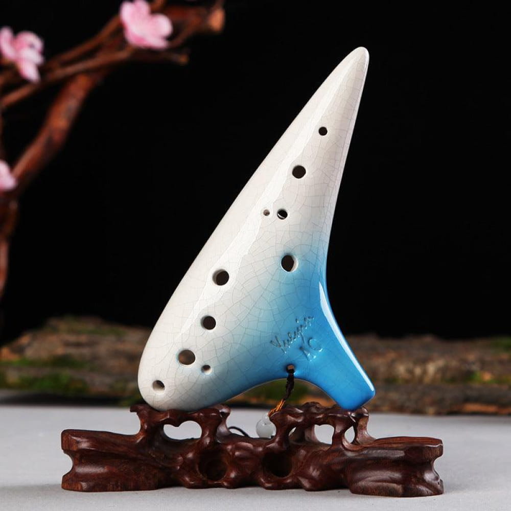 White and blue ceramic ocarina mounted on a wooden stand for musical performance