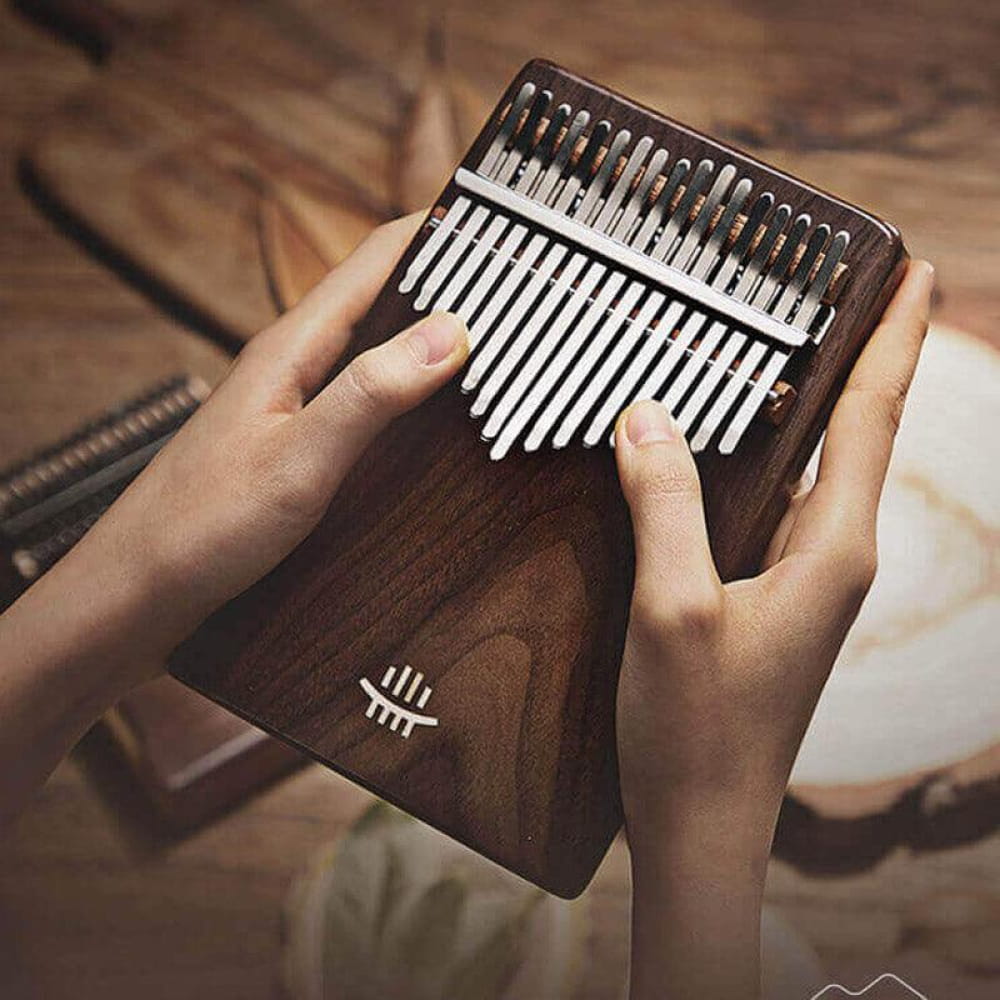 Wooden 17 Key Black Walnut C Tone Kalimba with metal tines held by hands
