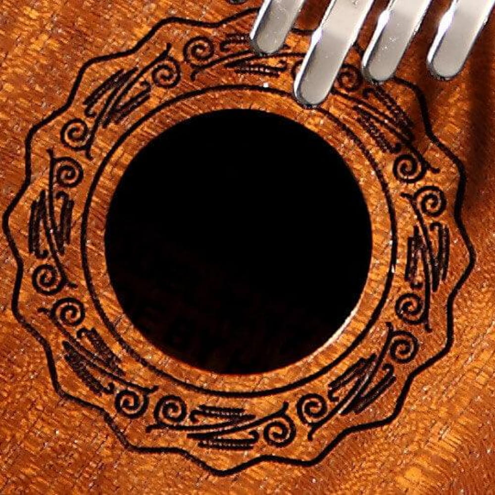 Ornate circular sound hole of a 17 Key Mahogany Kalimba with intricate patterns