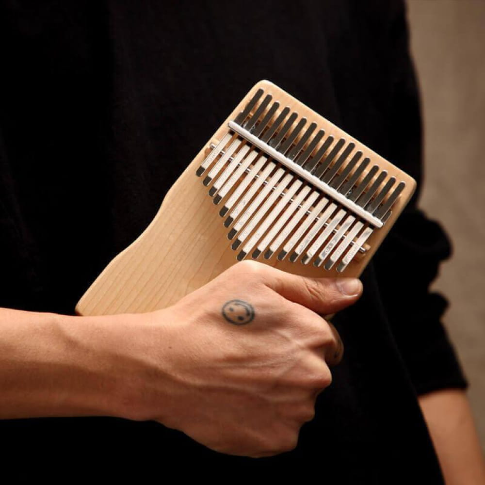Wooden Kalimba thumb piano with metal tines held in a hand for meditation music