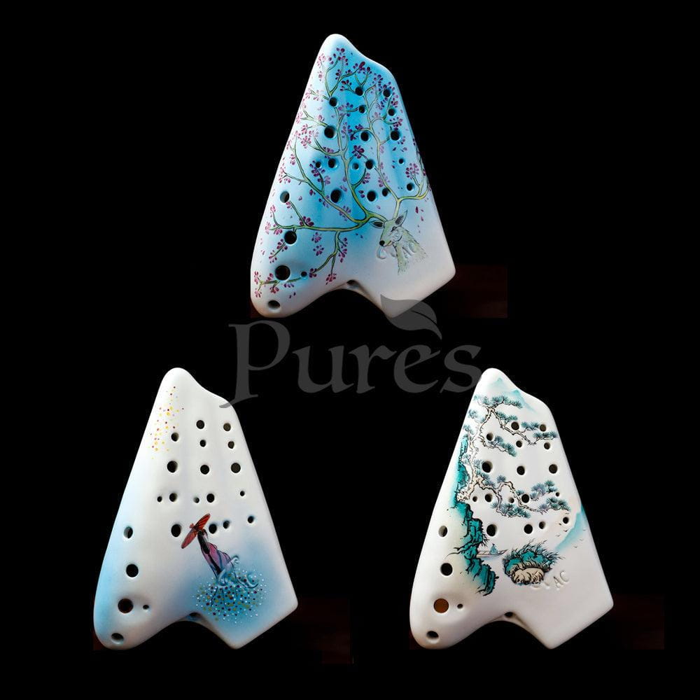Three white and blue ceramic ocarinas with decorative holes and painted designs