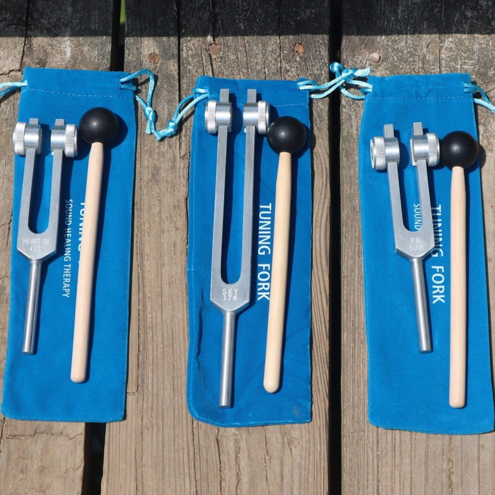 Three tuning forks with mallets on blue pouches for Solfeggio healing frequencies
