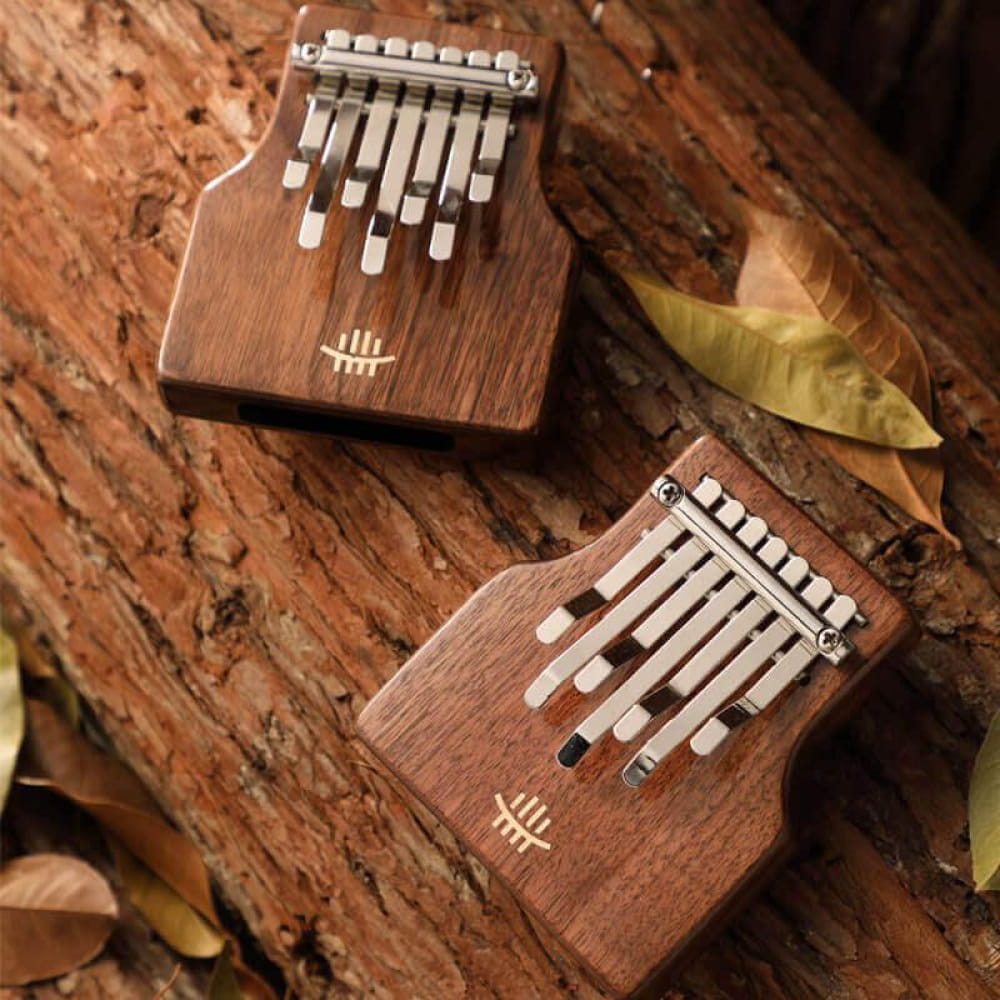 Two wooden kalimbas with metal tines displayed with 7-Key C Tone Thumb Piano