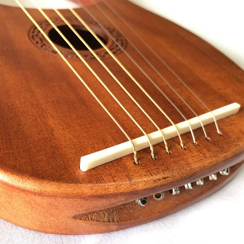 Wooden acoustic guitar bridge with white saddle and brass strings on a 7-String Lyre Harp