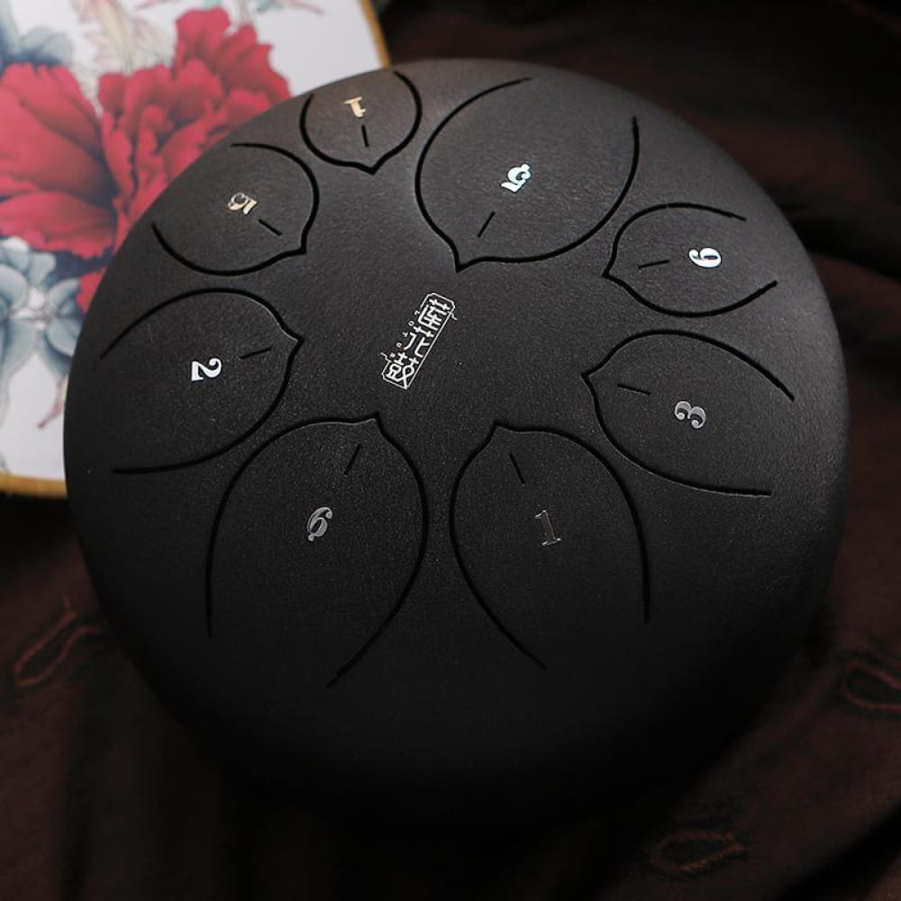 Black steel tongue drum with numbered tones in a circular pattern for musical harmony