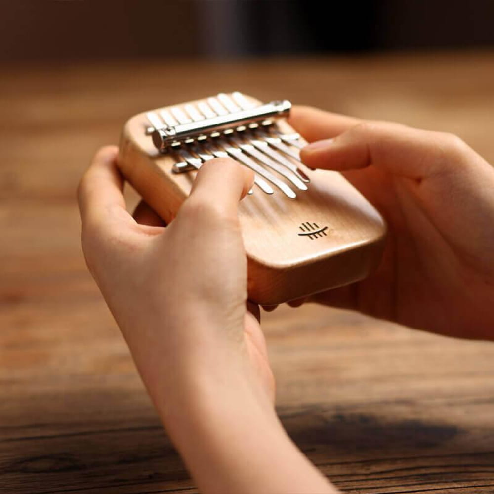 Kalimba thumb piano with metal tines played by hands, 8 Key Maple C Tone design