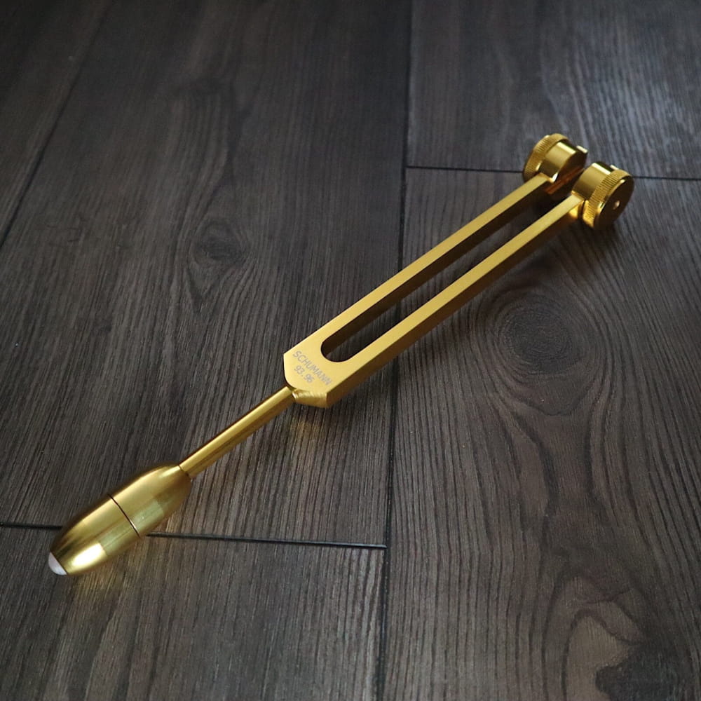 Golden tuning fork with sleek metallic design for 93.96 Hz Earth energy sound healing