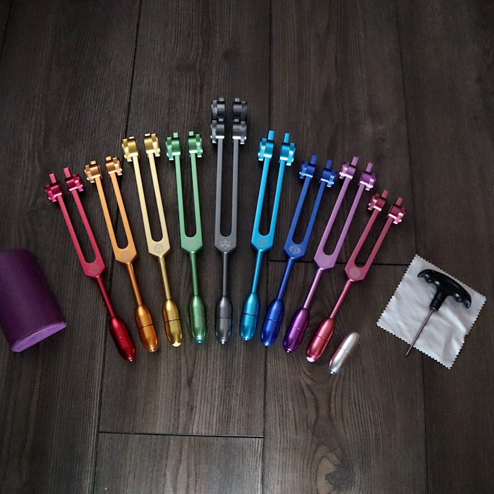 Rainbow-colored tuning forks in a fan pattern for Chakra healing and crystal massage