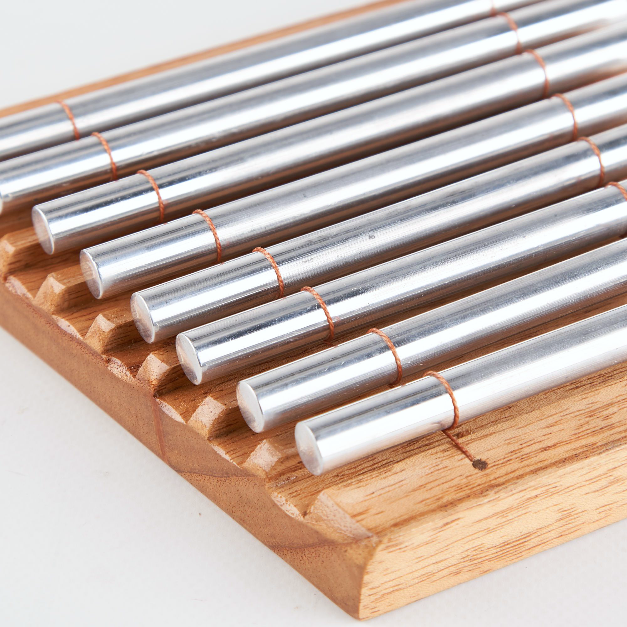 Metal rods arranged in parallel rows on a wooden holder for Chakra Energy Bar Chimes
