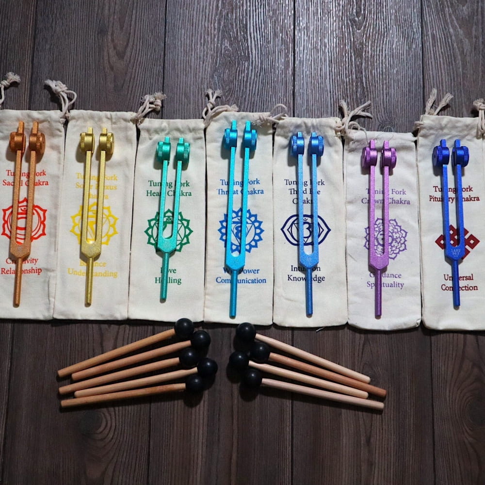 Colorful chakra-themed tuning forks with pouches and mallets for healing