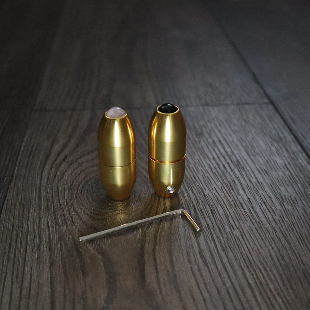 Two brass bullet cartridges and a metal pin on surface with massage handles
