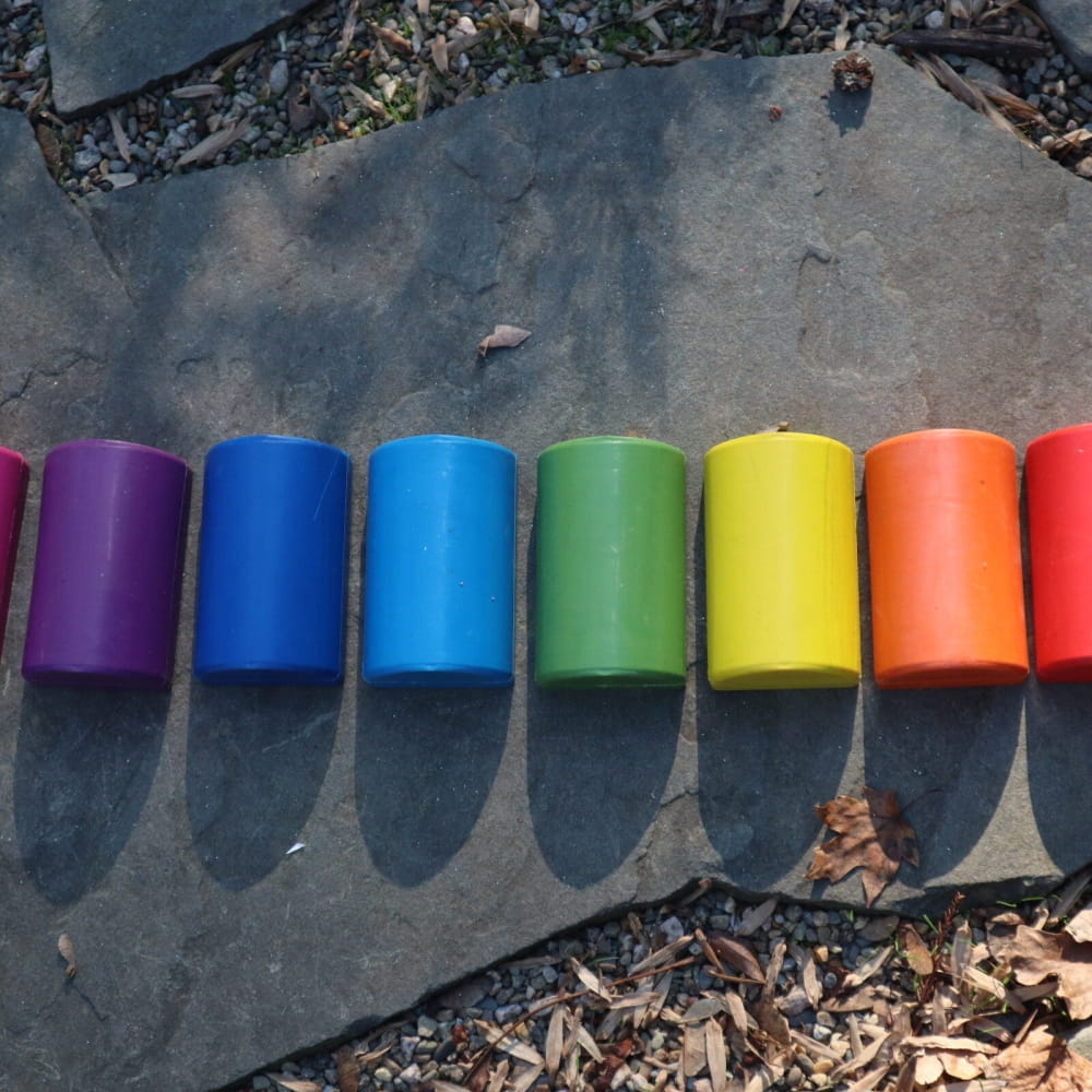Colorful cylindrical containers arranged in rainbow order for Healing Tuning Fork Activators