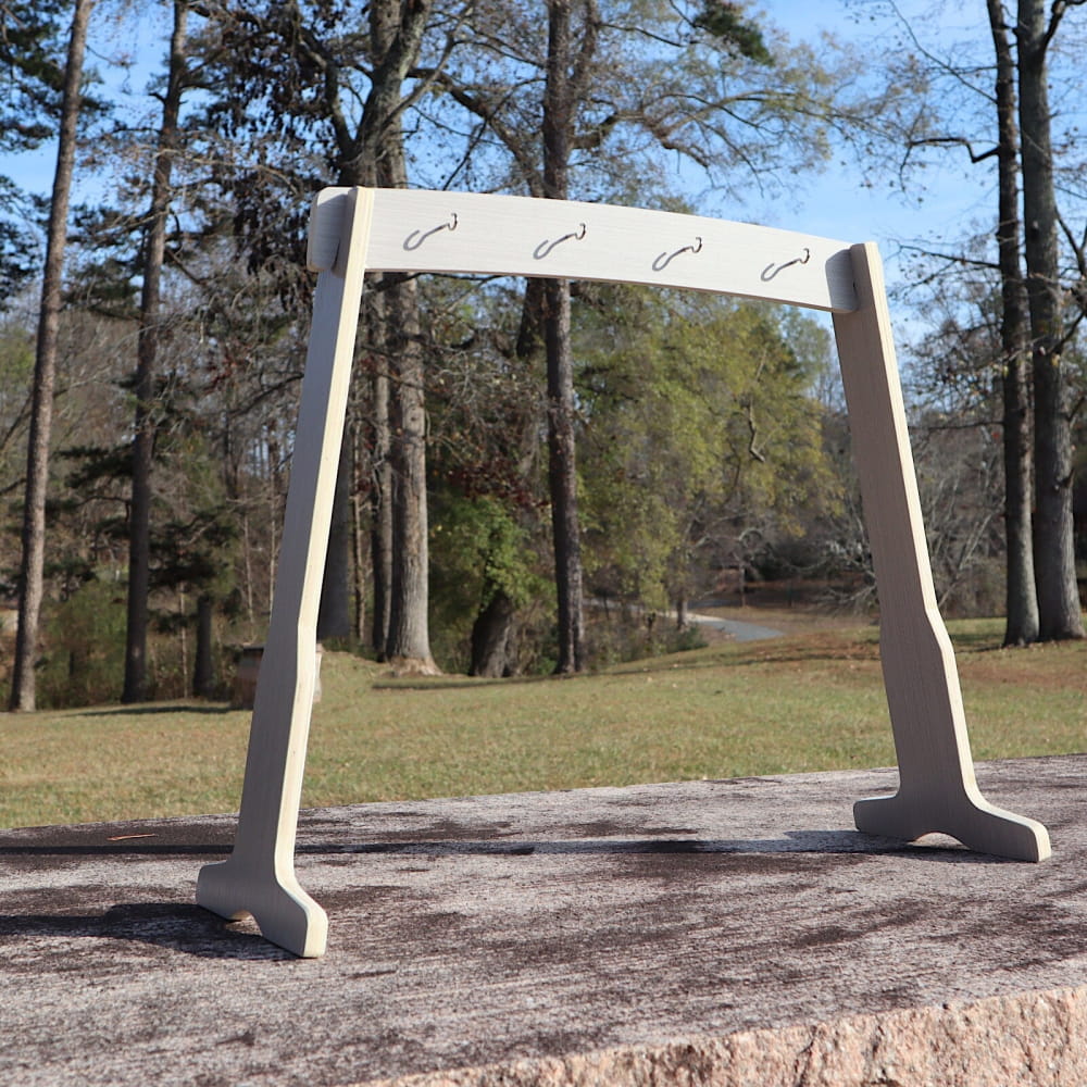 White metal arch stand for Melody Chimes with hooks on a concrete base