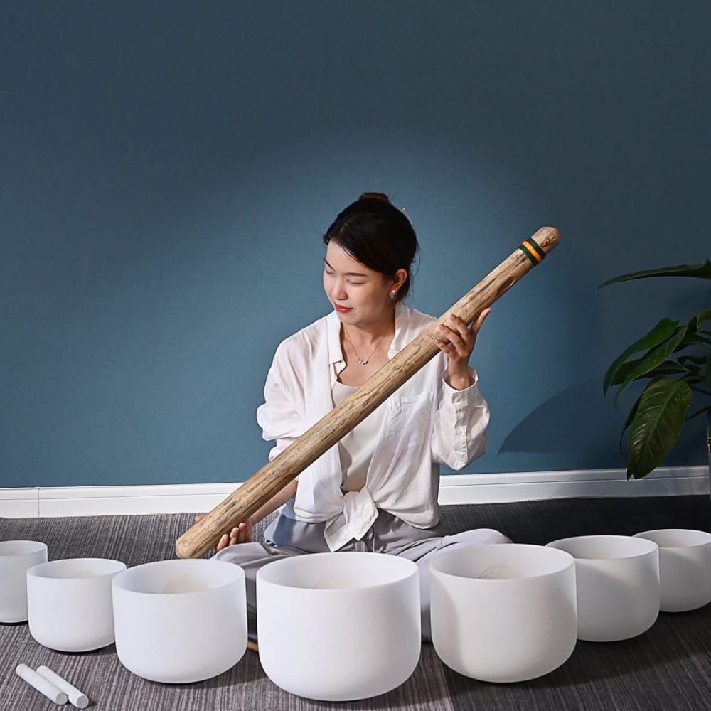 White crystal singing bowls in semicircle with a wooden mallet for sound healing
