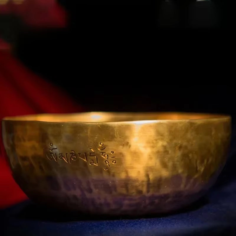 Golden Tibetan singing bowl with engraved script for meditation and healing